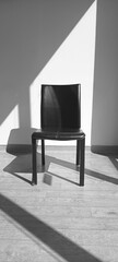 minimalist black chair in sunlit interior with in natural light that creates geometric shadows, interior design inspiration, photography aesthetics, modern lifestyle, on black and white photograph