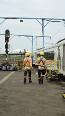 railway workers conducting safety inspection alongside train at station in high visibility safety...