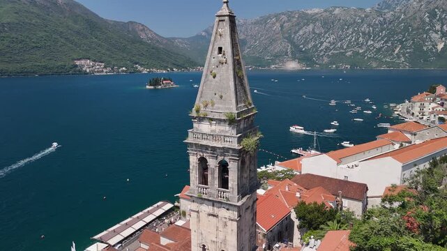 Aerial orbits church belltower in Perast, Our Lady of the Rocks beyond