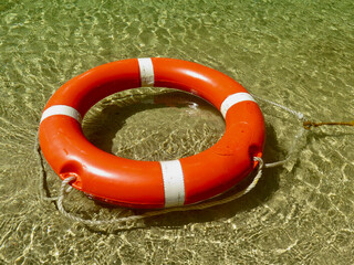 Life buoy on the surface of the water. A red life buoy with a rope floats on the surface of a...