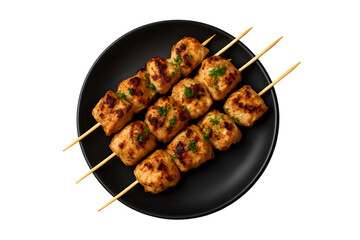 Grilled chicken skewers on a black plate overhead shot