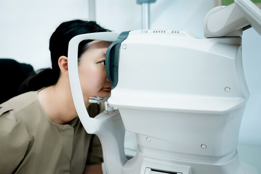 Woman undergoing eye examination using modern optical equipment