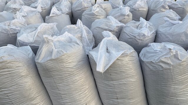 Many large white sandbags are piled densely together, creating a textured, monochromatic scene