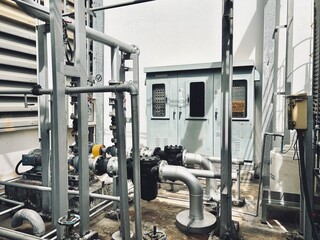 A complex arrangement of industrial pipes, valves, and electrical control panels in a factory setting. This intricate system is vital for regulating processes and managing operations in a modern plant