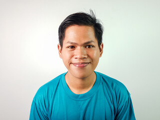 Fototapeta premium Portrait of Smiling Young Asian Man Wearing a Blue Shirt on a White Background
