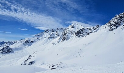 Snow-covered mountain landscape in the high alpine region of the Engadin, Swiss Alps, beneath a bright blue sky