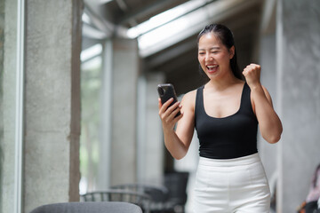 Excited businesswoman celebrating success on smartphone in office