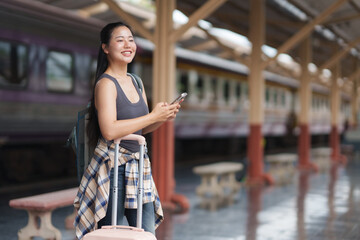 Young woman using smartphone while waiting for train at railway station