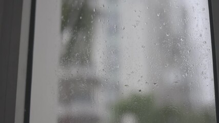 Shot from a window on a rainy day, with water droplets sliding down the glass during daylight - Powered by Adobe