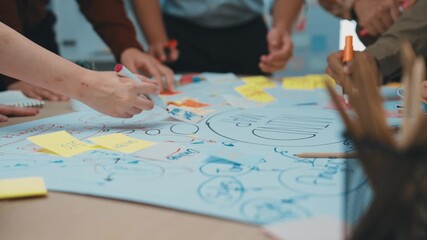 Engaging brainstorming session with diverse team members actively discussing ideas, using sticky notes, and sketching concepts on a large paper within a creative workspace. SACTR