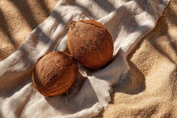 Whole coconut with tropical leaf shadow on sandy beach