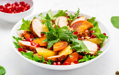Autumn salad with grilled chicken, persimmon, pomegranate, walnuts, oranges and lettuce, top view