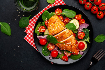 Vegetable salad with grilled chicken fillet, fresh spinach, tomatoes, cucumber and red onion, top view