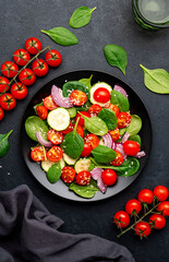 Healthy salad with spinach, tomatoes, cucumber, onion, sesame and olive oil, top view