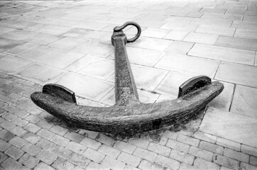 Large vintage anchor resting on cobblestone and stone pavement