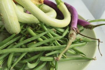 Unusually shaped vegetables on plate. Zucchini and eggplant, asparagus beans. Seasonal food and farm organic produce.