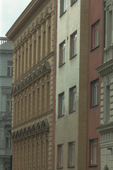 A long row of various buildings are neatly lined up on a bustling city street, showcasing the architecture of the urban landscape