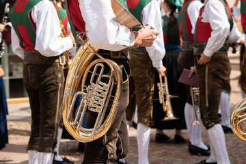 Men in lederhosen and traditional south tyrol folk clothing of St Christina, Santa Cristina, Val Gardena, during annual folklore festival with musical brass instruments in summer 