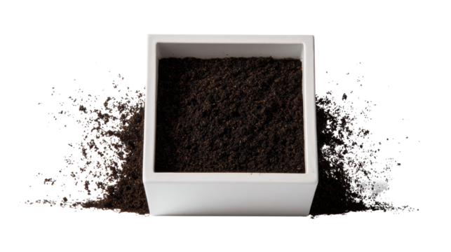 Ground coffee in a white container with scattered coffee grounds around it, isolated on a white background.