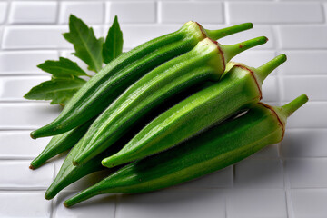 Fresh Green Okra Vegetable Pods Stacked on White Tile Background