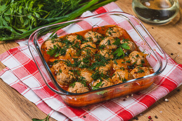 Meatballs in tomato sauce in a baking dish with herbs