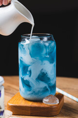 Milk is added to a glass of blue tea