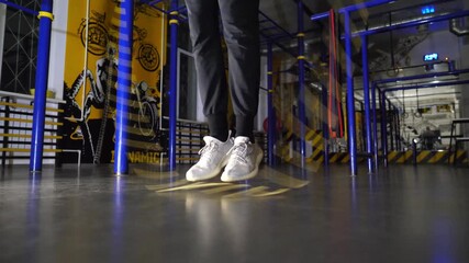 Legs of young sportsman skipping with a jump rope at sport club. Male feet of athlete exercising in fitness centre. Sporty man in sportswear doing cardio at modern gym. Concept of active lifestyle - Powered by Adobe