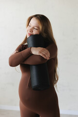 Portrait active pregnant caucasian woman embracing yoga routine with foam roller