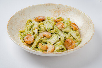 A vibrant dish of pesto pasta featuring shrimp, herbs, and a sprinkle of cheese, ready to enjoy