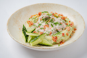 A stunning plate features creamy mashed potatoes topped with crispy bacon, herbs, and cucumber