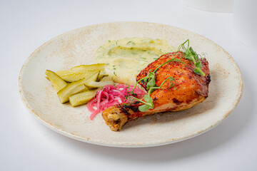 Crispy grilled chicken leg with smooth mashed potatoes and zesty pickles
