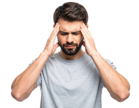 A young man with a beard wearing a gray t-shirt is touching his temples and appears to be experiencing a headache or deep concentration.