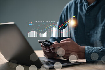 Business research report charts show growth as a person uses a smartphone to collect data, while a...