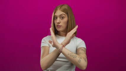 Obraz premium Young blonde woman making stop gesture with crossed arms against vibrant pink background