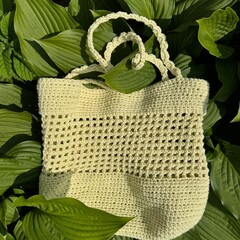 handmade yellow summer crochet bag on green leaves