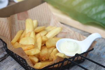 A basket of thick-cut golden French fries served on printed paper