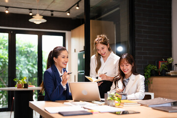 Confident mature business professional woman talking to younger female colleague at office table,...