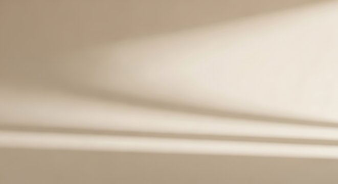Abstract beige background with sunlight casting soft shadows from a window.