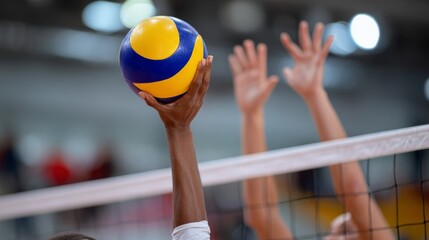 Volleyball player is holding a ball in the air. The ball is yellow and blue. The player is wearing a white shirt