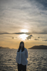Fototapeta premium 夕日の海にいる女性