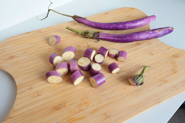 Sliced unusually shaped eggplant on wooden cutting board. Healthy food and vegetables. Organic seasonal farm products.