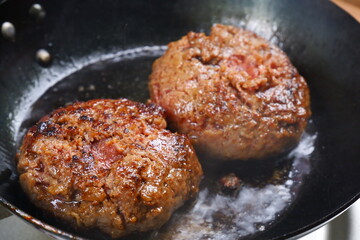 ハンバーグ - フライパンでハンバーグステーキを、ジュージュー音をさせながら焼く
