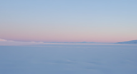 Obraz premium Tranquil Arctic Vista: An awe-inspiring scene of the Arctic landscape, where the sky gently blushes above a serene expanse of clouds and distant mountains, capturing a sense of stillness and wonder.