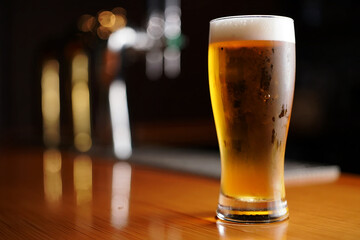 Frosted glass of golden beer with foamy head beverage drink