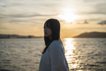 夕日の海にいる女性