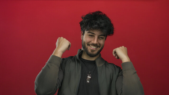 Young man with beard expressing happiness against red background, showcasing a cheerful and friendly demeanor, perfect for depicting positive emotions.