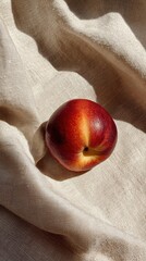 Ripe nectarine fruit resting on textured beige fabric under soft sunlight ideal for summer wellness concepts, seasonal nutrition ads and natural lifestyle visuals