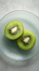 Top view of two halves of fresh kiwi fruit placed on frosted glass plate perfect for healthy food visuals, tropical nutrition ads and natural lifestyle compositions