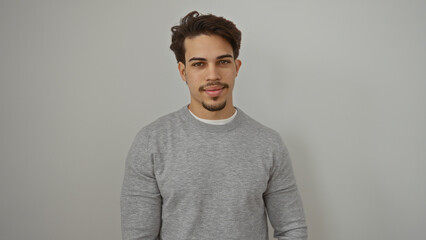 Young hispanic man standing confidently against a plain white background exuding an attractive and...