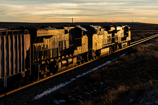 Modern locomotives glint in the last light as they head west